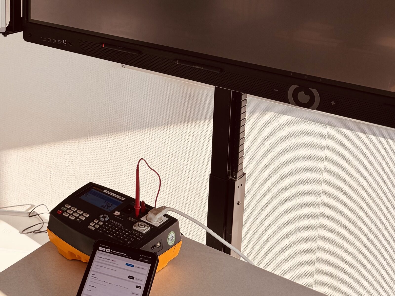 Prüfgerät und Prüf-App vor der Tafel während der Prüfung